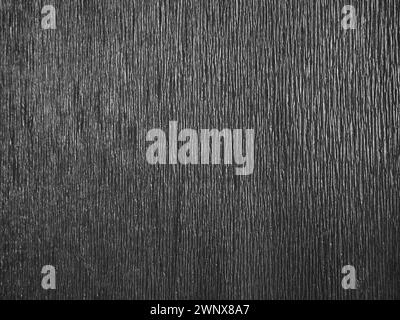 Black or gray corrugated paper. Uneven surface. Abstract monochrome background. Wavy edges of the paper sheet. Lighting gradient. Corrugated texture Stock Photo