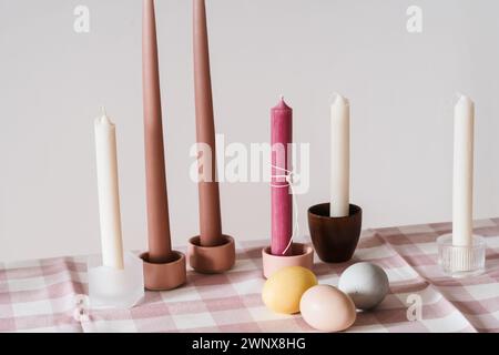 Easter place setting with candles and multi colored eggs, linen tablecloth, white background Stock Photo