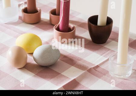 Easter place setting with candles and multi colored eggs, linen tablecloth Stock Photo