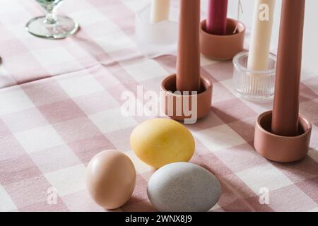 Easter place setting with candles and multi colored eggs, linen tablecloth Stock Photo