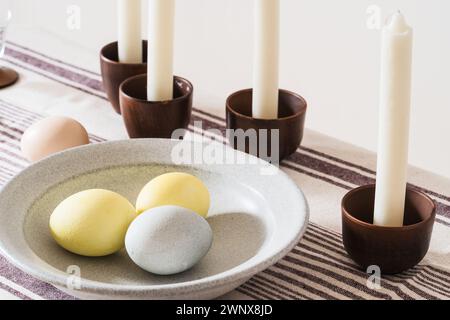 Easter place setting with candles and multi colored eggs, linen tablecloth Stock Photo