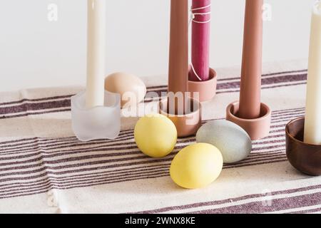 Easter place setting with candles and multi colored eggs, linen tablecloth Stock Photo