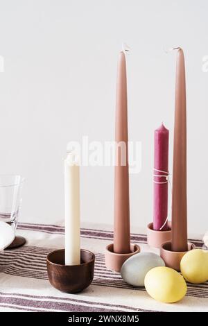 Easter place setting with candles and multi colored eggs, linen tablecloth Stock Photo