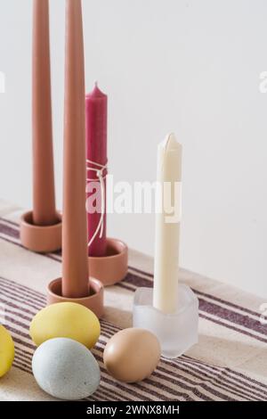 Easter place setting with candles and multi colored eggs, linen tablecloth Stock Photo