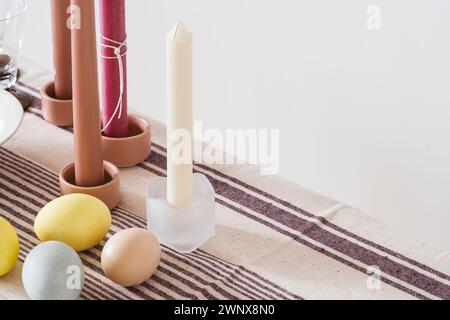 Easter place setting with candles and multi colored eggs, linen tablecloth Stock Photo