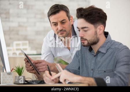 focused senior and young colleague discussing online project Stock Photo