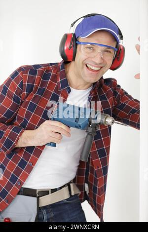 jovial mature man using a drill Stock Photo