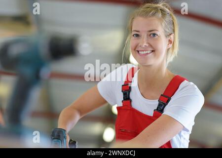 female apprentice using drill in factory Stock Photo