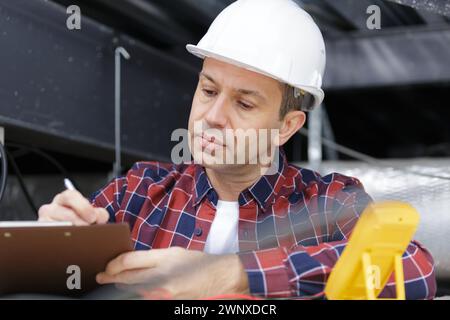 mature contractor writing on clipboard Stock Photo