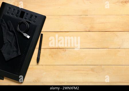 Graphic tablet, stylus, glove and USB-cable on wooden background Stock Photo
