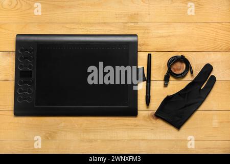 Graphic tablet, stylus, glove and USB-cable on wooden background Stock Photo