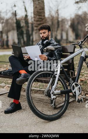 Stylish businessman reviewing documents in park with bicycle Stock Photo