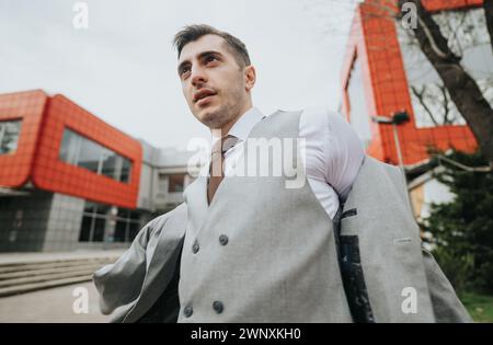 Serious young business professional attentively reviews documents amidst a flurry of activity from associates outdoors. Stock Photo