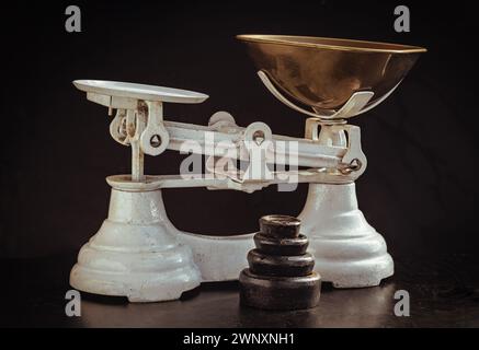 Old obsolete manual weighing scales and Iron Brass Tray with set of cast iron weights. Classic weight scale Isolated on dark background, Antique balan Stock Photo