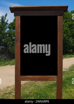 Blank black vertical rectangular pylon stand on forest dirt road mock up. Empty panel for advertisement, promotion mockup. Clear canvas frame banner Stock Photo