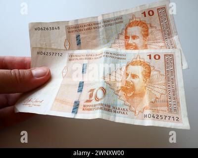 The convertible mark Bosnian konvertibilna marka is the national currency of Bosnia and Herzegovina. BiH currency. A womans hand holds two banknotes Stock Photo