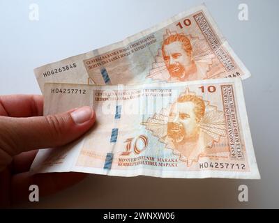 The convertible mark Bosnian konvertibilna marka is the national currency of Bosnia and Herzegovina. BiH currency. A womans hand holds two banknotes Stock Photo