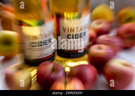 A zoom burst background of bottles of vintage cider surrounded by apples. Stock Photo