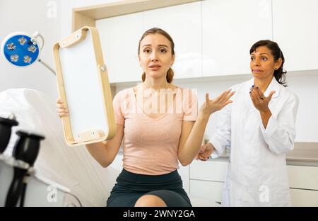 Dissatisfied woman checking result after cosmetology procedure Stock Photo