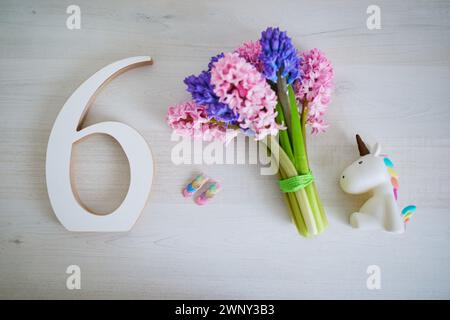 Bunch of light pink and purple hyacinths and white wooden number six. Sixth birthday or anniversary concept. Stock Photo