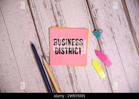 Wooden man shows with a hand to white board with text business district, concept. Stock Photo
