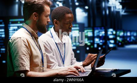 System administrators running analysis on servers helping businesses manage databases, host websites and store files. Technicians auditing data center equipment used for high performance computing Stock Photo