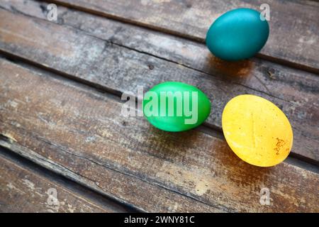 Multi-colored eggs painted with gouache and onion peel close up on wooden background. Three boiled eggs. Postcard poster for Easter. Easter holiday Stock Photo