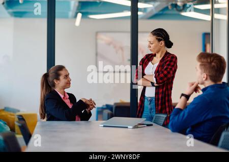 A team of successful programmers sits in a startup office, strategizing new business projects and solving existing challenges, showcasing innovation Stock Photo