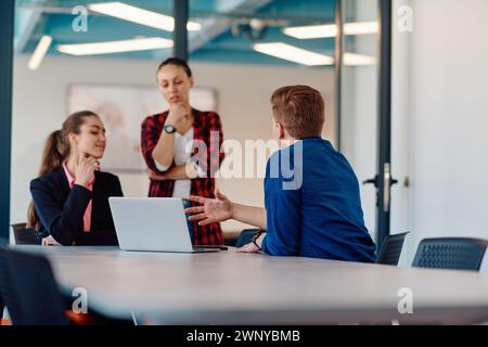 A team of successful programmers sits in a startup office, strategizing new business projects and solving existing challenges, showcasing innovation Stock Photo
