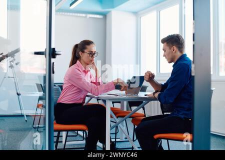 In a sleek, modern glass office, the director engages in a productive discussion with an employee, focusing on business projects and fostering Stock Photo