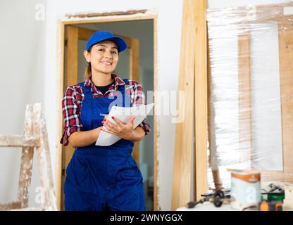 Positive woman builder with documents in apartment Stock Photo