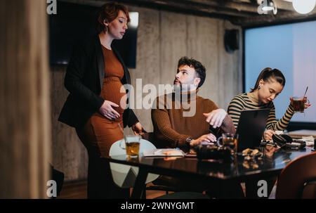 Young professionals working late, collaborating on a project for business growth, discussing sales statistics, revenue, and budgeting for expansion. Stock Photo