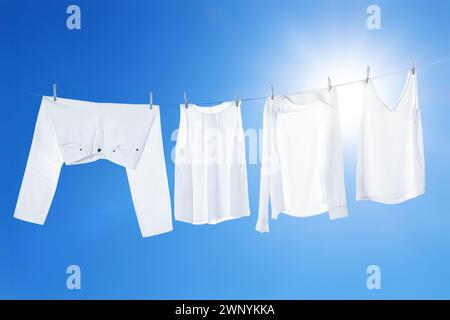 Different clothes drying on washing line against blue sky Stock Photo