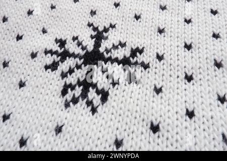 Jacquard knitted pattern. Geometric ornament for Christmas or New Year. Knitted black snowflakes and dots on a white background. Winter trendy modern Stock Photo
