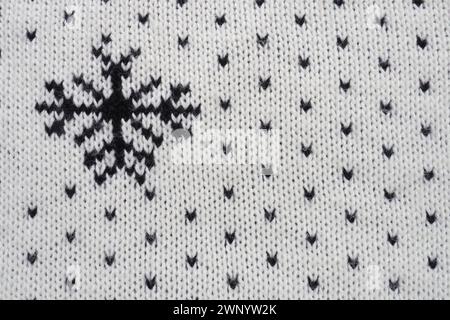 Jacquard knitted pattern. Geometric ornament for Christmas or New Year. Knitted black snowflakes and dots on a white background. Winter trendy modern Stock Photo