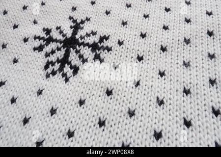 Jacquard knitted pattern. Geometric ornament for Christmas or New Year. Knitted black snowflakes and dots on a white background. Winter trendy modern Stock Photo