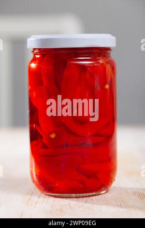 Pickled peppers in a glass jar on wooden table Stock Photo