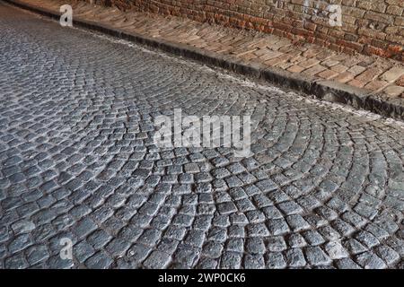 Paving stones - a hard road surface, a kind of pavement, lined with flat rectangular bars of the same shape and size. Block stone from which the road Stock Photo