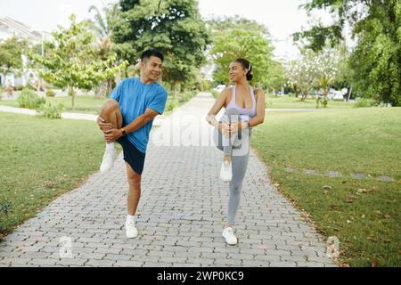 Happy diverse couple doing leg stretch exercise before morning run Stock Photo