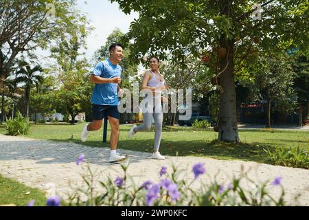 Positive diverse couple jogging in park to stay fit Stock Photo