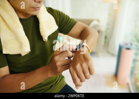 Cropped image of fit man checking pulse on his tracker after working out at home Stock Photo