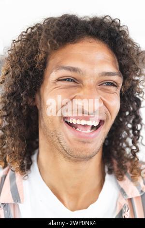 Young biracial man with curly hair laughs joyfully, showcasing a positive mood Stock Photo