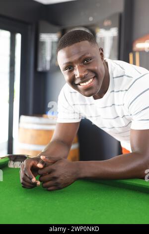 A young African American man smiles while leaning on a pool table Stock Photo