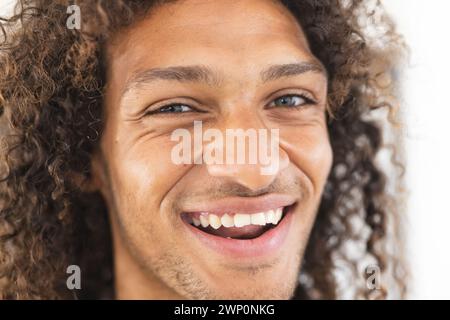Young biracial man with curly hair smiles brightly Stock Photo