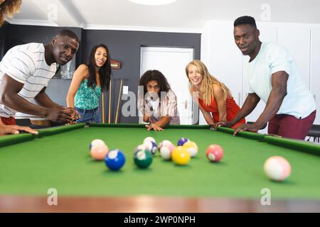 Diverse group of friends playing pool, focused on the game Stock Photo