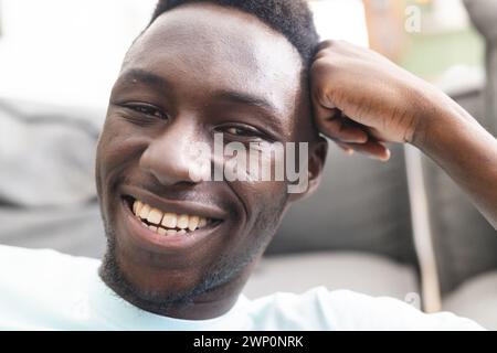 Young African American man with a bright smile, resting his hand on his head Stock Photo