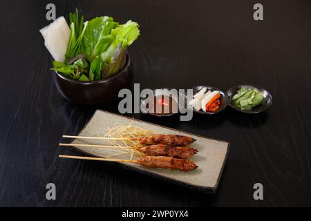 Nem nuong also know as grilled spring rolls, vietnamese food isolated on black wood table background Stock Photo
