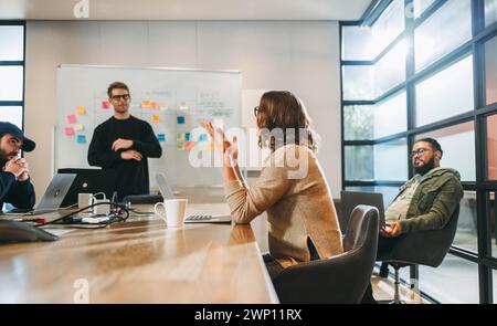 Diverse professionals engage in a collaborative discussion. Seated in a well-lit boardroom, they brainstorm project management and software developmen Stock Photo