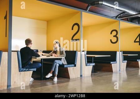 Developer and programmer engaging in discussion and teamwork, focusing on computer programming and software development. They sit together in a cowork Stock Photo