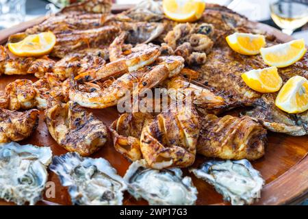 Grilled mix seafood on wooden plate. Charcuterie platter board with shrimp, oysters, fish, squids and octopus in fish restaurant. Healthy diet food Stock Photo